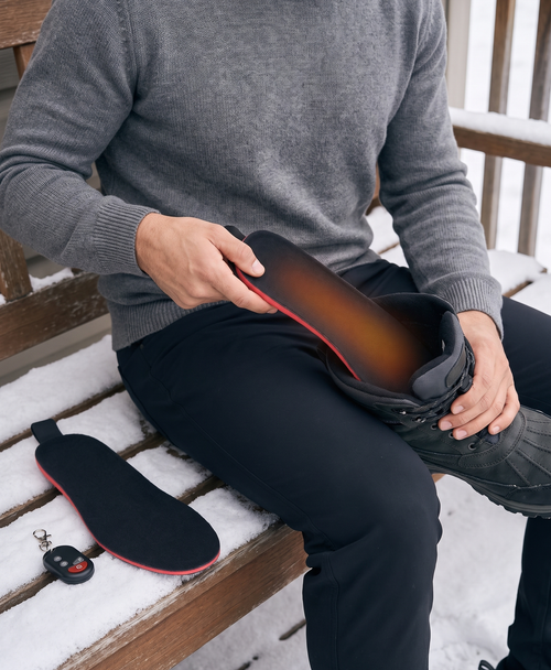 Boot stepping through snow with a warm glow on the sole, shown with black heated insoles for winter walking