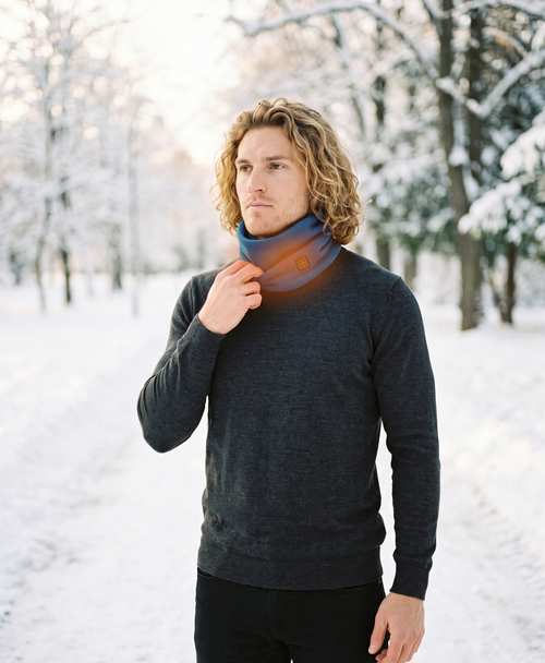 Man outdoors in winter wearing the blue heated fleece neck gaiter with an orange heat glow at the back of the neck