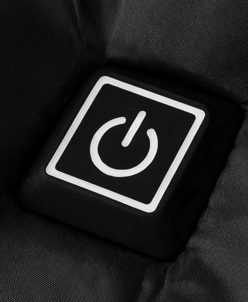Close-up of the chest power button and front zip on the black heated puffer jacket