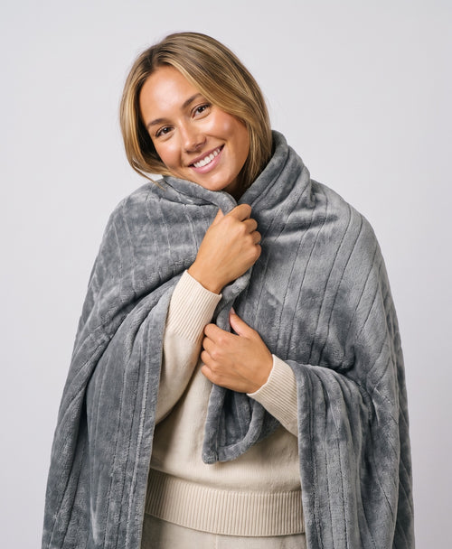 Woman wrapped in the Coziva electric heated blanket in grey flannel