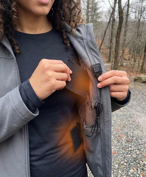 Hand holding a flexible black carbon fiber heating pad, showing how it folds and bends