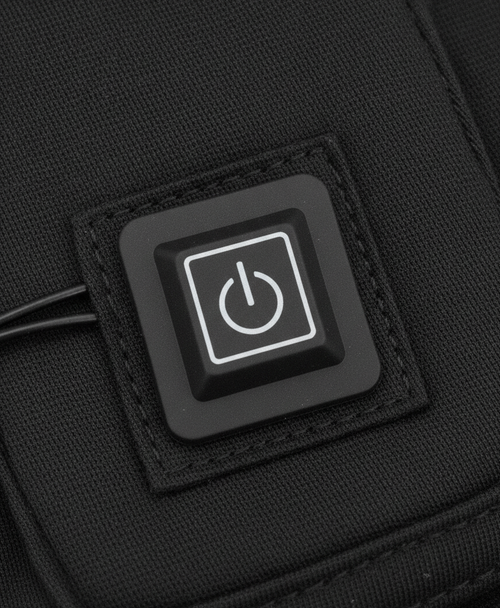 Close-up of the round power button controller on the heating pad set sewn into black fabric