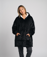 Woman in a black heated wearable blanket hoodie with white sherpa hood, studio portrait
