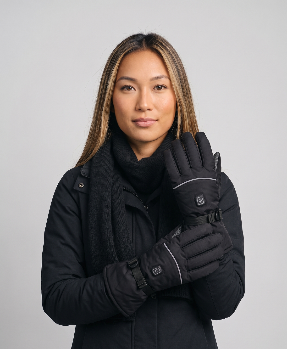 Pair of black heated gloves with reflective stripe, power button and adjustable wrist strap on the back of each glove