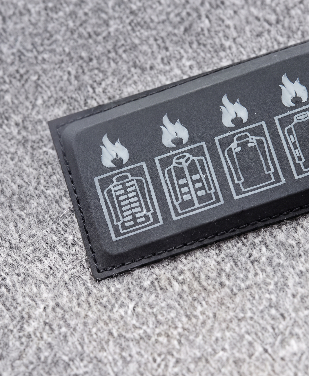 Close-up of the 4-button control panel on the chest of the gray heated hoodie with LED heat level indicator