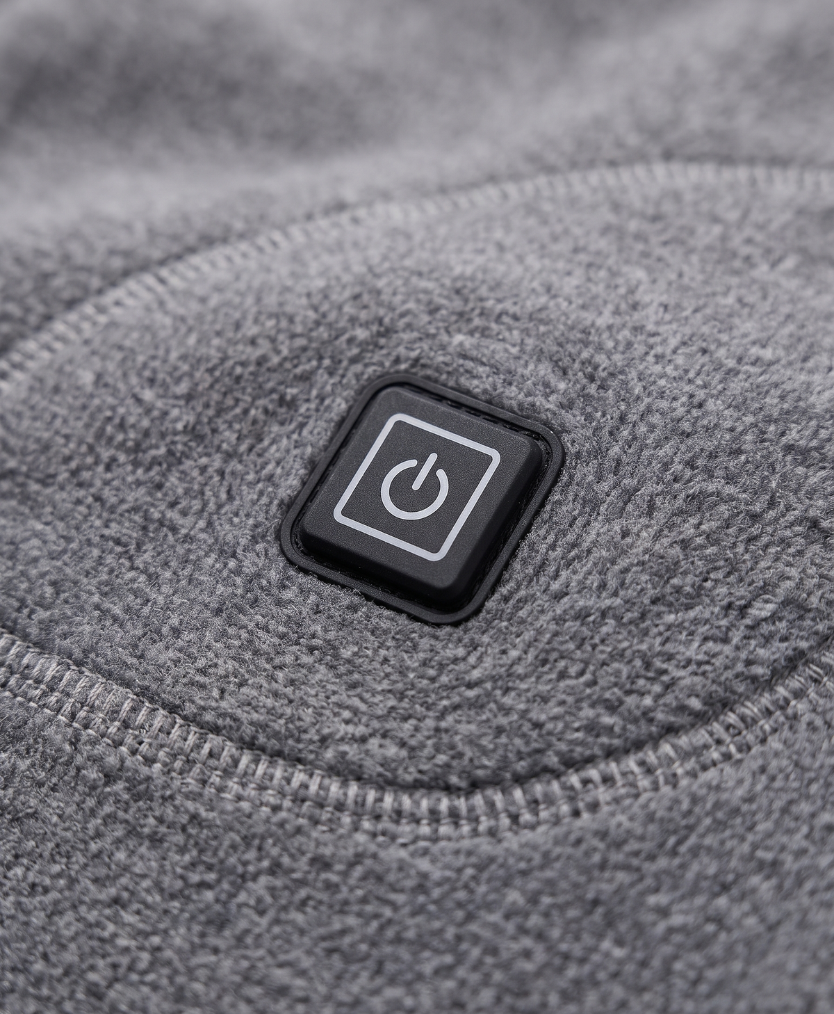 Close-up of the gray heated thermal top showing the heating icon patch at the lower side and the soft knit fabric