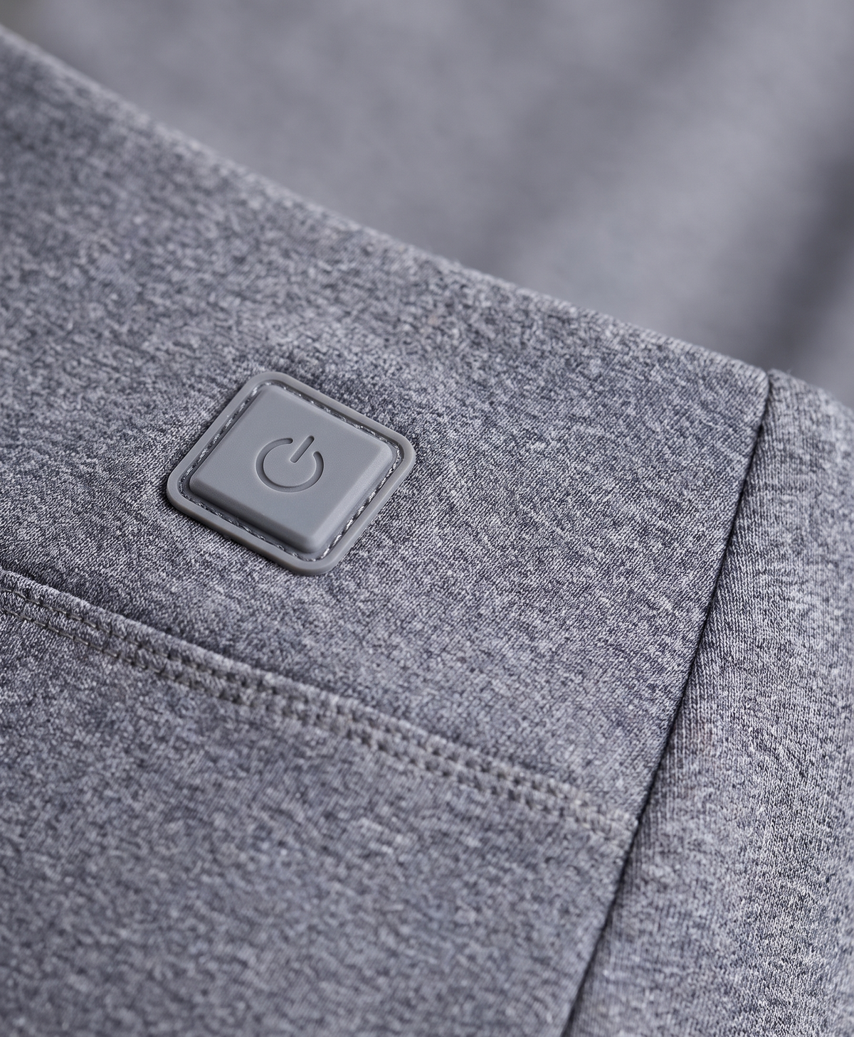 Close-up of the grey thermal pants showing the heating button patch at the hip, knee seam panel and waistband
