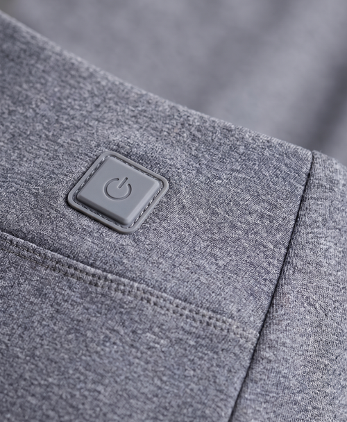 Close-up of the grey thermal pants showing the heating button patch at the hip, knee seam panel and waistband