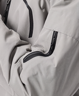 Close-up of the khaki jacket's drawstring hood, high collar, zippered chest pocket and zippered sleeve pocket