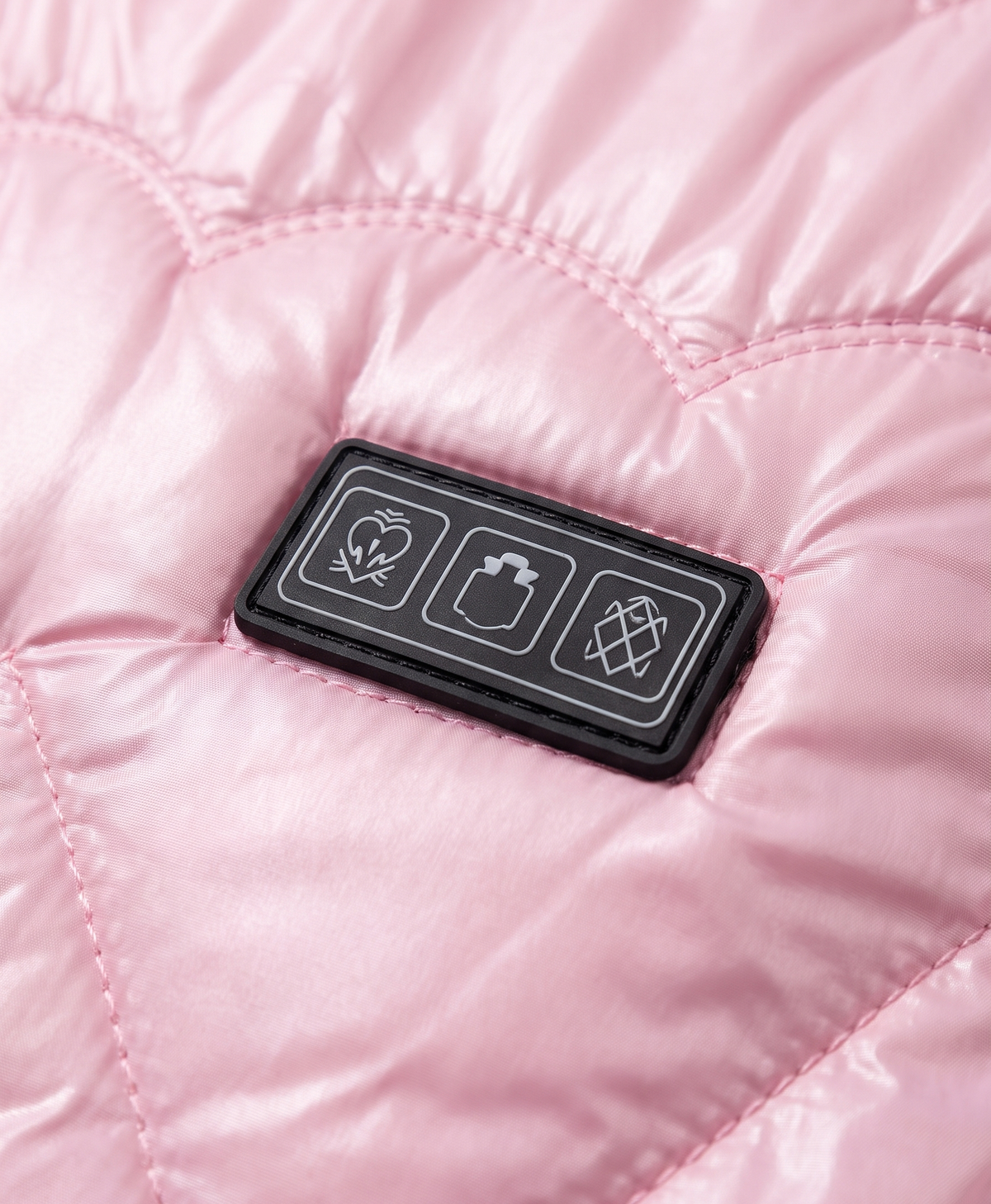 Close-up of the three-control panel on the chest and heart-pattern quilted stitching of the pink heated vest