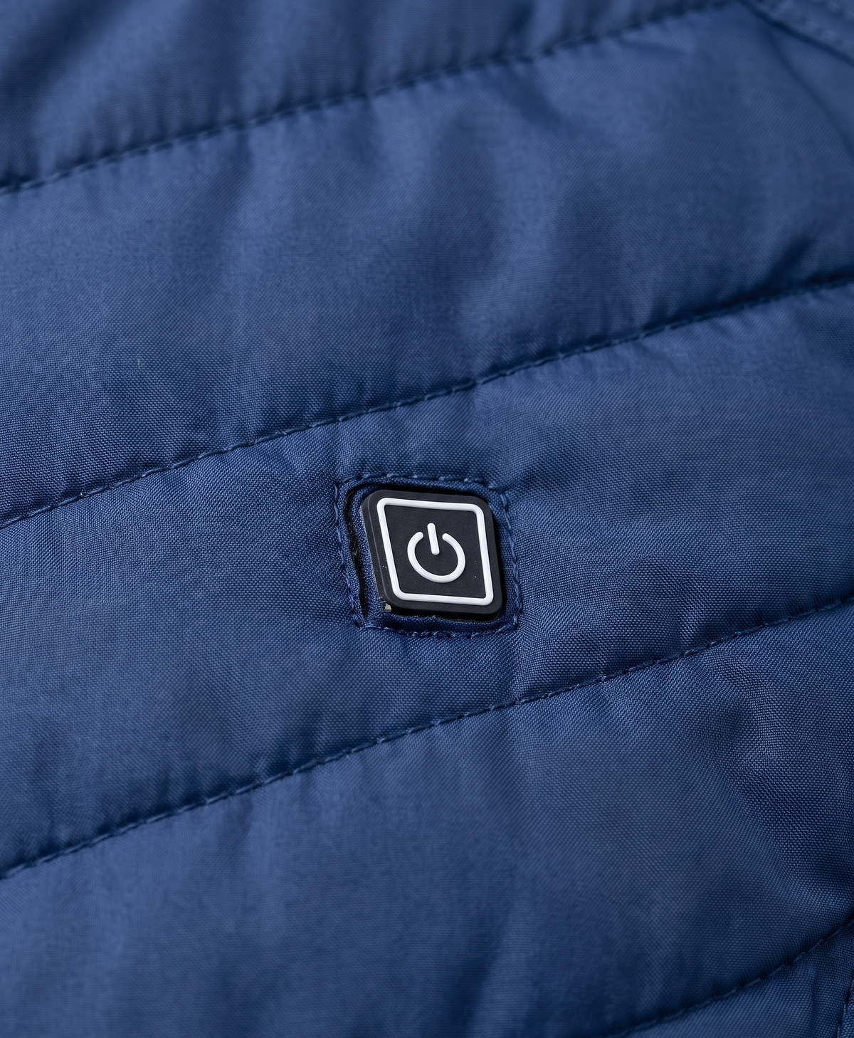 Close-up of the chest power button and zip on the blue quilted heated vest