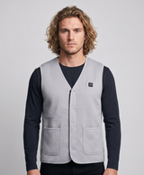 Gray quilted men's heated vest with V-neck, front zip, chest power button and two patch pockets, shown on a flame background