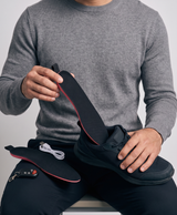 Pair of black heated insoles for men, top and underside, with the red heating grid glowing