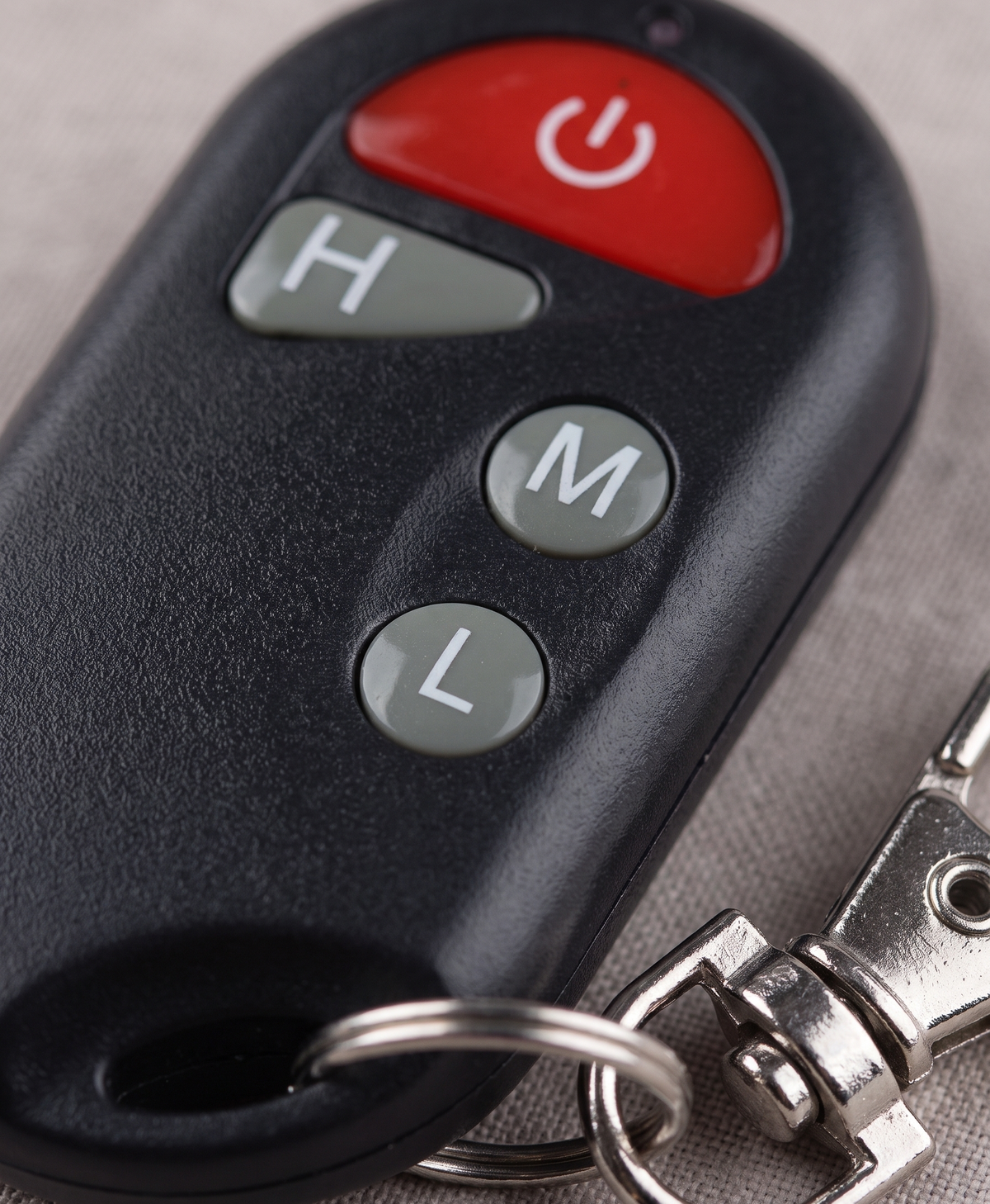 Close-up of the insole remote control with power, H, M and L buttons and a key ring clip