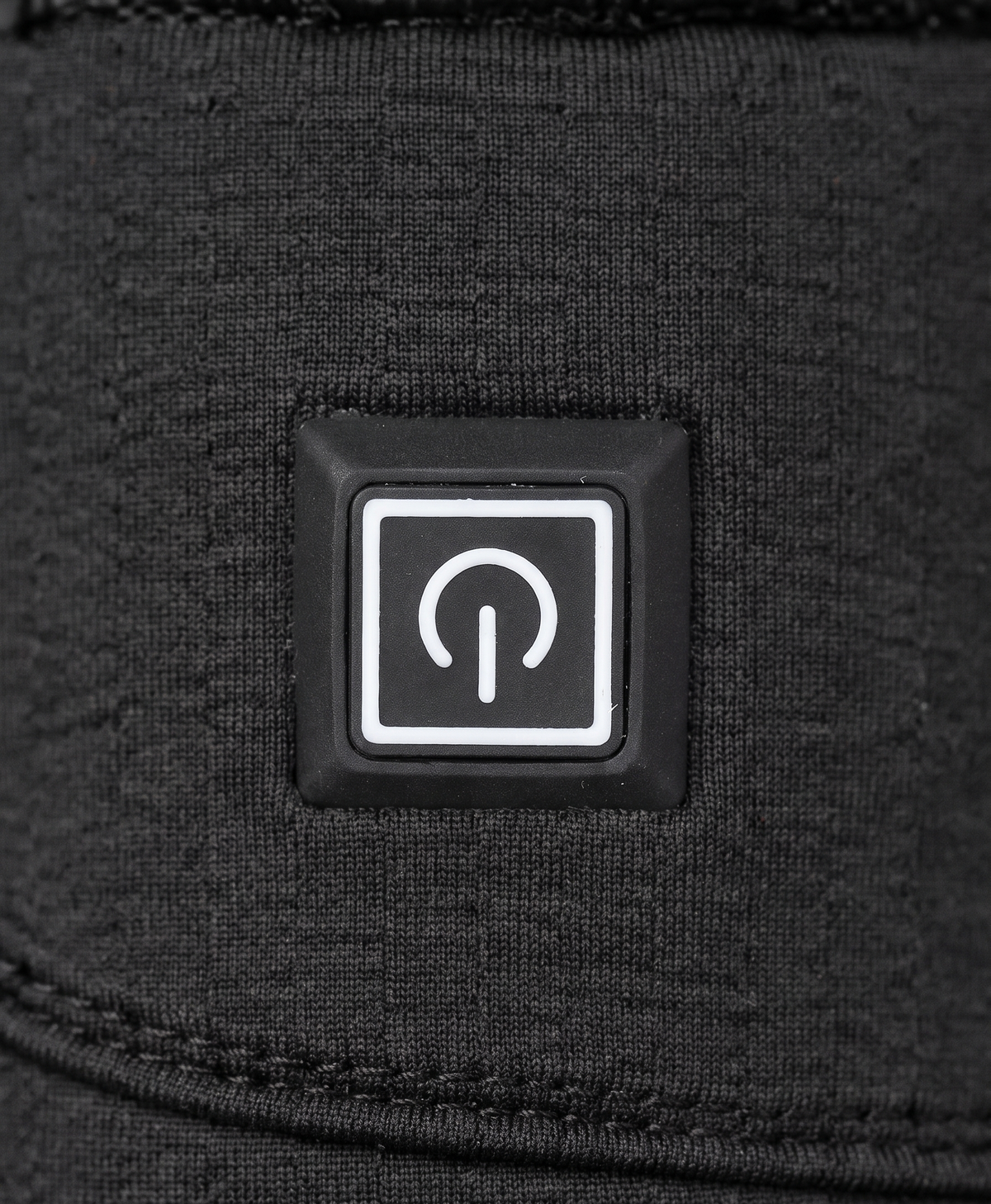 Close-up of the black glove's power button, adjustable wrist strap with buckle and quilted back of hand
