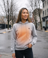 Lifestyle photo of a model in the gray heated hoodie holding a power bank beside the front kangaroo pocket