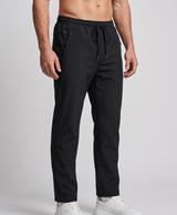 Two people wearing black waterproof heated pants with drawstring waist against a snowy mountain backdrop